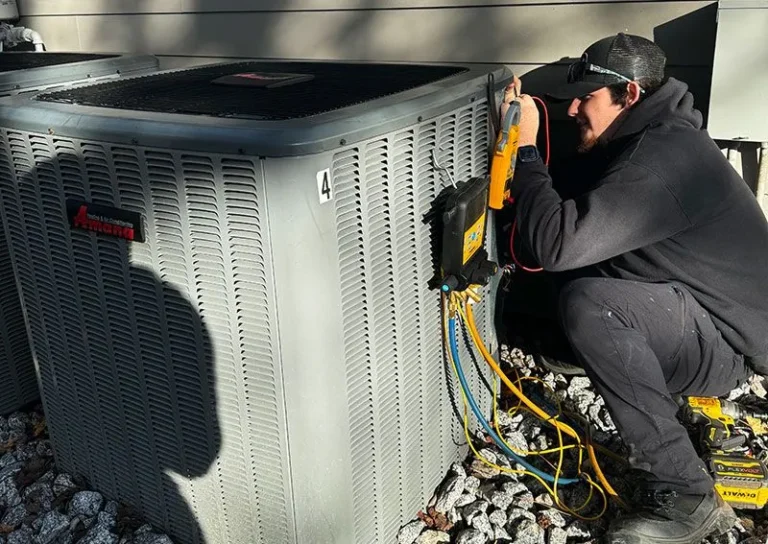 Technician inspecting and repairing an outdoor HVAC unit at night.